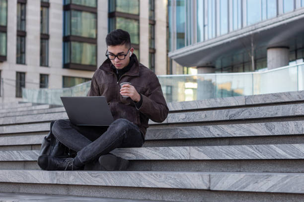 istock young male Asian student programmer freelancer work outdoors with laptop 1203822960
