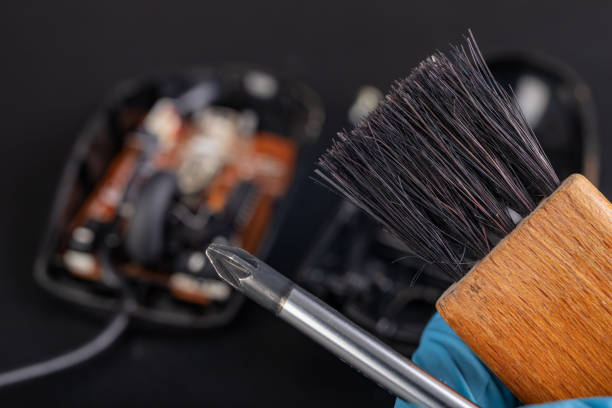 istock Cleaning of an optical computer mouse with a brush. Keeping the computer workplace clean. Dark background. 1203823168
