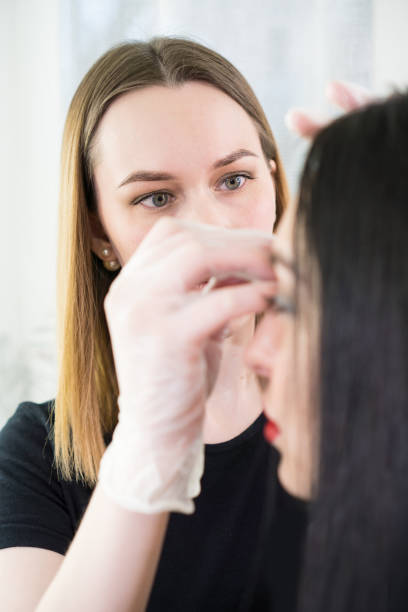 istock Professional eyebrow correction. Woman having professional eyebrows correction in studio. Vertical composition. 1203824339