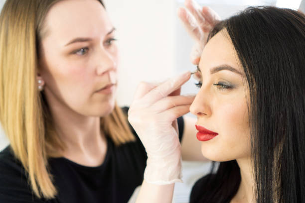 istock Eyebrow correction. Beautiful brunette woman having professional eyebrows correction in studio. 1203824342