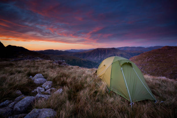 Wild camp on top of the Lake District mountains at sunset Green backpacking tent pitched for a wild camp on top of Cold Pike fell with a view of the Langdale Pike mountains in the English Lake District with a spectacular pink sunset. langdale pikes stock pictures, royalty-free photos & images