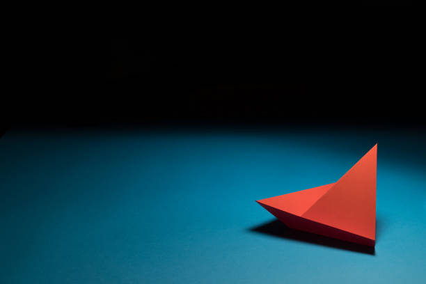 istock Explore: An origami sailing boat on a blue background 1203827148