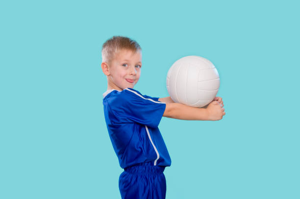 배구공을 가진 파란색 셔츠를 입은 행복한 어린 아이. 물리적, 스포츠. - volleyball child indoors sport 뉴스 사진 이미지