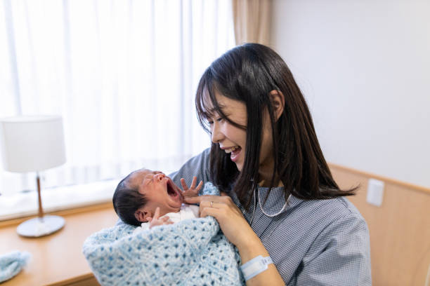 jeune mère retenant le nouveau-né à l'hôpital - baby yawning asian ethnicity newborn photos et images de collection