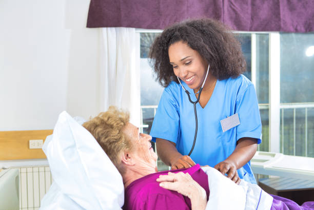 istock Nurse with stethoscope smiling to elderly patient lying in bed 1203835284