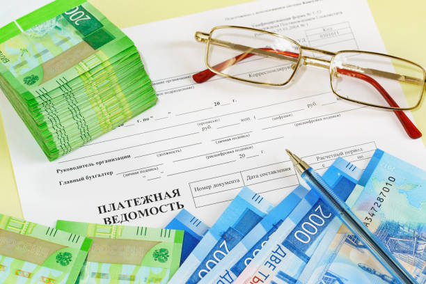 istock Glasses, Russian money, a pen, and a payroll form on the table 1203836545