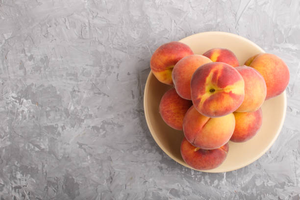 Fresh peaches on a plate on gray concrete background. top view, flat lay, copy space.