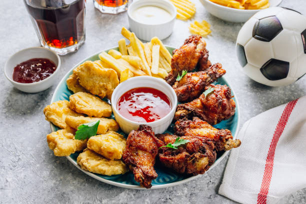 mesa fof saboroso lanches para cerveja preparado para assistir esportes na tv. frango. asas de frango, nuggets de frango, batatas fritas, batatas fritas, vários molhos e limonada. fundo cinza claro. foco seletivo - american football football food snack - fotografias e filmes do acervo