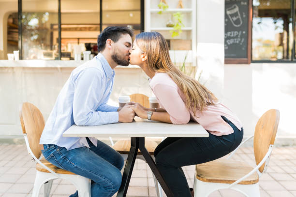 istock Hispanic Couple Kissing At Sidewalk Cafe 1203840563