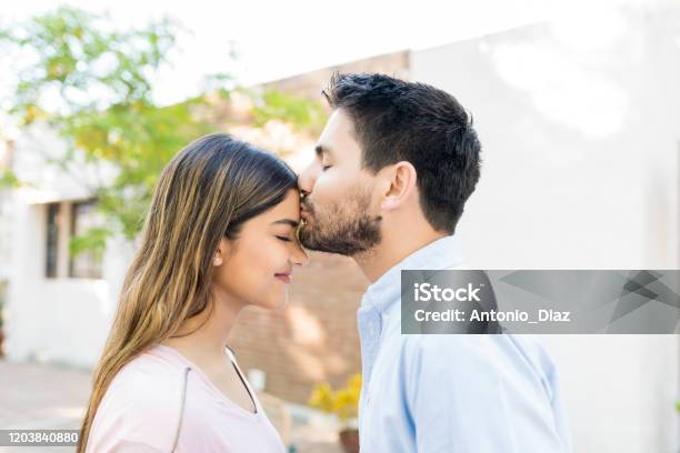 Man Kissing Forehead Of Girlfriend Outside Cafe Stock Photo - Download Image Now - Forehead, Kissing, Men