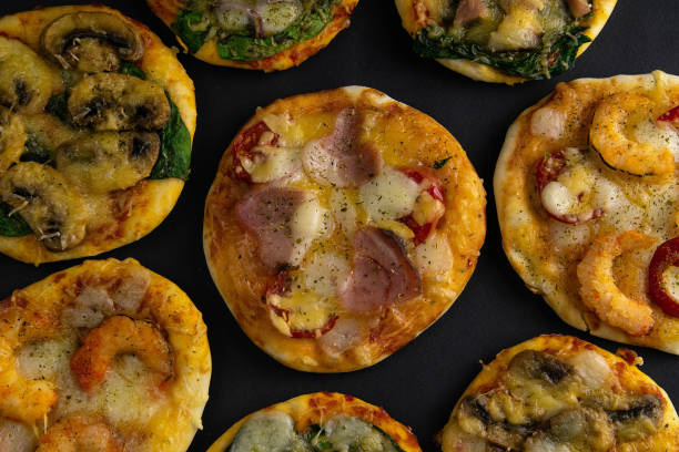istock Small mini pizza. Set of different mini pizzas. Pizza: with shrimp, with mushrooms, with spinach and onions, with bacon, with paperoni, with tomatoes 1203841774