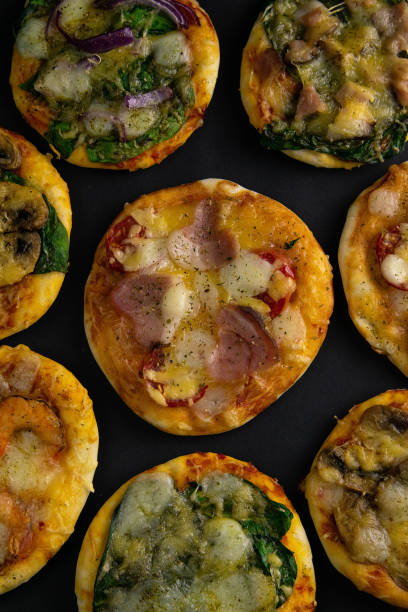 istock Small mini pizza. Set of different mini pizzas. Pizza: with shrimp, with mushrooms, with spinach and onions, with bacon, with paperoni, with tomatoes 1203841775