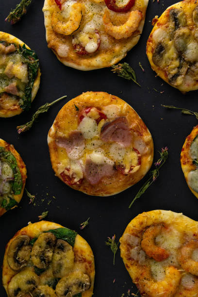 istock Small mini pizza. Set of different mini pizzas. Pizza: with shrimp, with mushrooms, with spinach and onions, with bacon, with paperoni, with tomatoes 1203841778