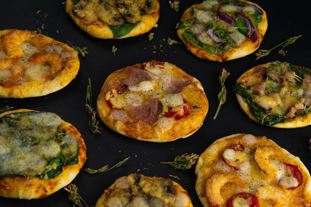 istock Small mini pizza. Set of different mini pizzas. Pizza: with shrimp, with mushrooms, with spinach and onions, with bacon, with paperoni, with tomatoes 1203841976