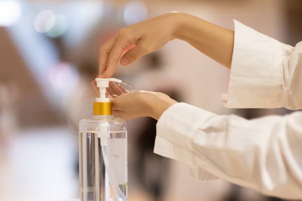 a girl using alcohol gel for cleaning hands - swine flu fotos imagens e fotografias de stock