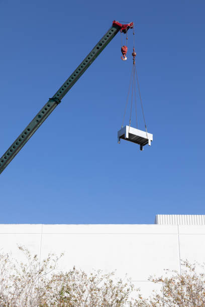 Crane installing an air conditioning unit on building roof top, Florida, USA