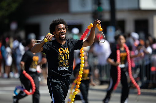 Chicago, Illinois, USA - August 8, 2019: The Bud Billiken Parade, Man and children jumping a rope made of balls promoting McDonalds
