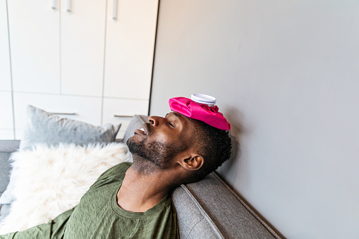 A young black man lying with ice pack on his head