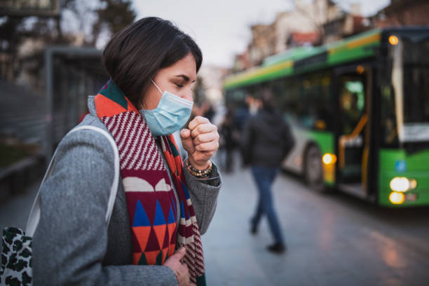 Woman Wear Face Mask And Coughing While Standing In The Town Side view of woman wear face mask and coughing while standing in the town, looking down avian flu virus photos stock pictures, royalty-free photos & images