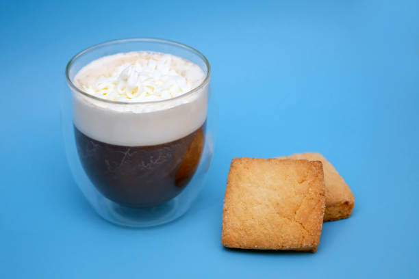 transparentes glas mit kaffee auf blauem hintergrund. - biscotti coffee cappuccino latté stock-fotos und bilder