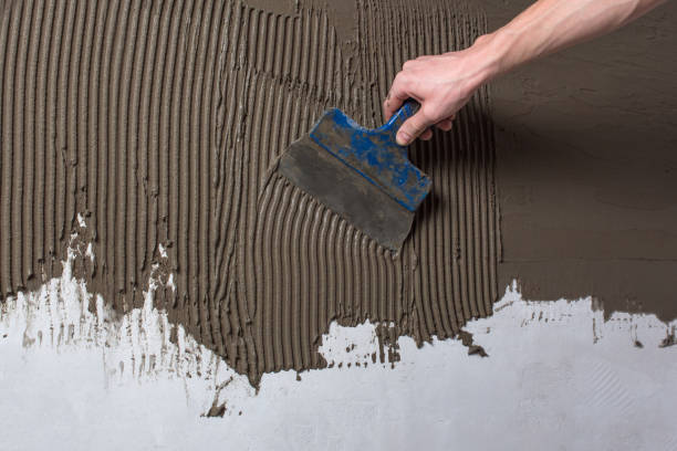 Repair the wall. Plastering the wall.Hand holding a spatula with construction mix.Applying putty or tile glue to the wall.Plaster the wall with a putty knife.Internal construction and finishing works