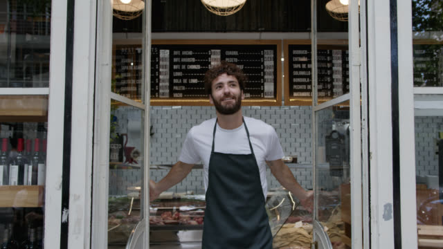 Happy young man opening for service at the butcher’s shops looking away daydreaming