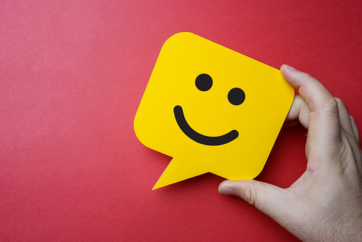 Experiencia de servicio al cliente y encuesta de satisfacción empresarial. Hombre sosteniendo burbuja de habla amarilla con la cara sonriente sobre fondo rojo. photo