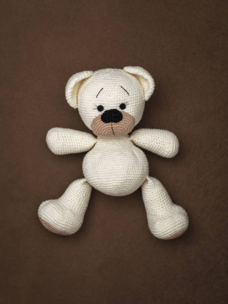 istock Top view of a white bear cub lying on a brown background. 1203887470