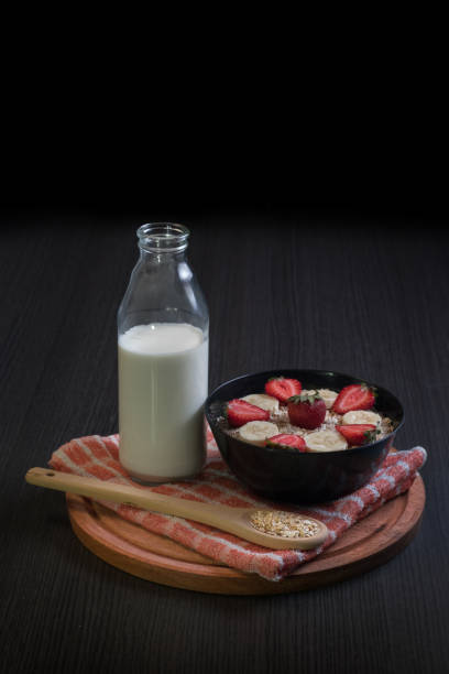 Bowl with strawberry and banana oatmeal with a bottle of milk stock photo