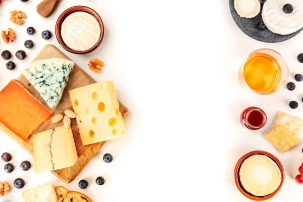 istock Cheese design, an overhead shot on a white background with a place for text. A variety of cheeses with wine and fruits, forming a frame for copyspace 1203897416