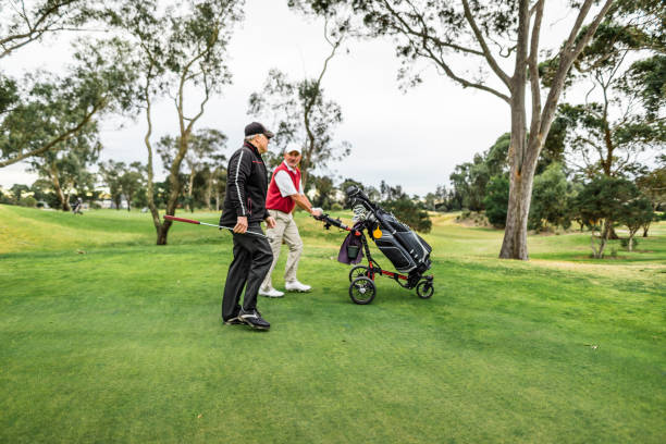 istock Smiling senior man pushing his clubs on a golf course 1203897441