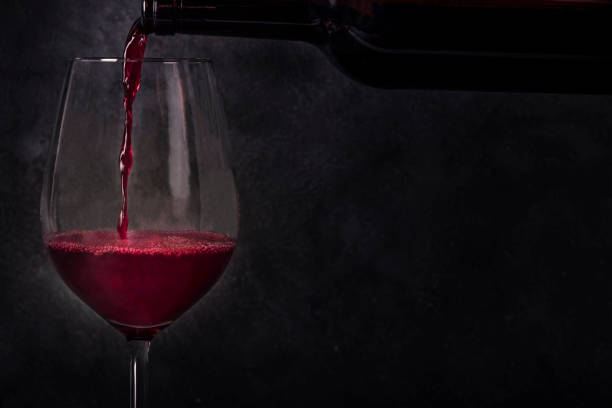 ボトルからグラスにワインを注ぎ、テキストの場所を持つ黒い背景の側面図 - ボジョレ ストックフォトと画像