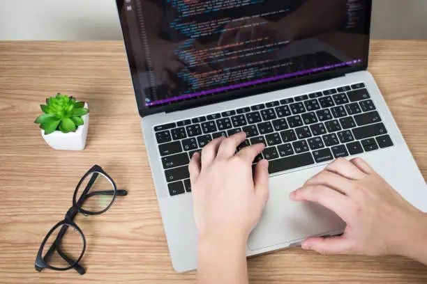 The hands of programmers are creating code on the laptop screen.