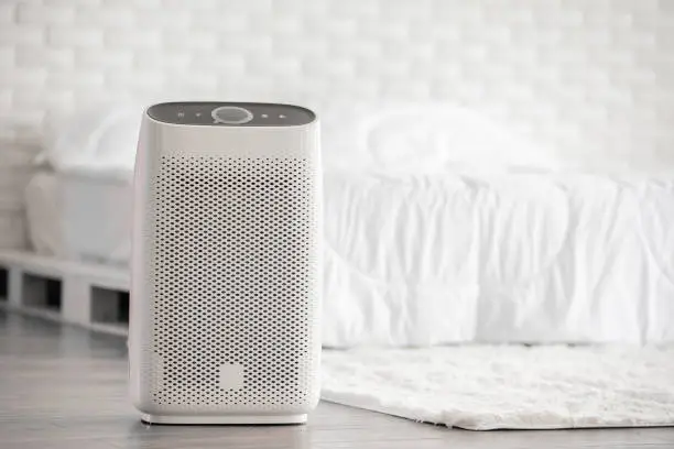 Photo of Air purifier in cozy white bed room for filter and cleaning removing dust PM2.5 HEPA in home,for fresh air and healthy life,Air Pollution Concept