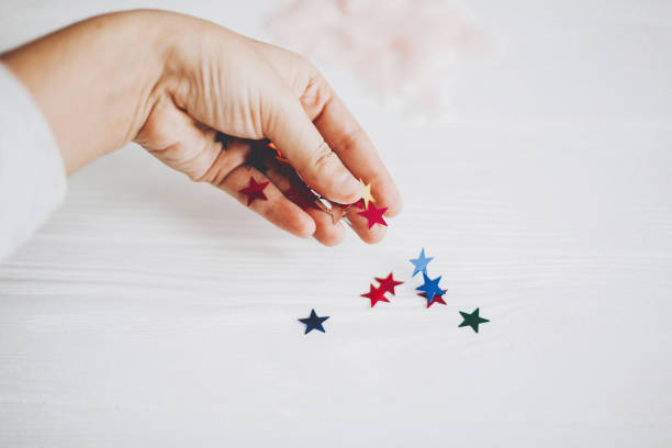 istock Hand holding colorful sparkling stars decorations on white background. Stylish atmospheric image. Happy birthday concept. Holiday decor. Magic in hand. Christmas 1203902863