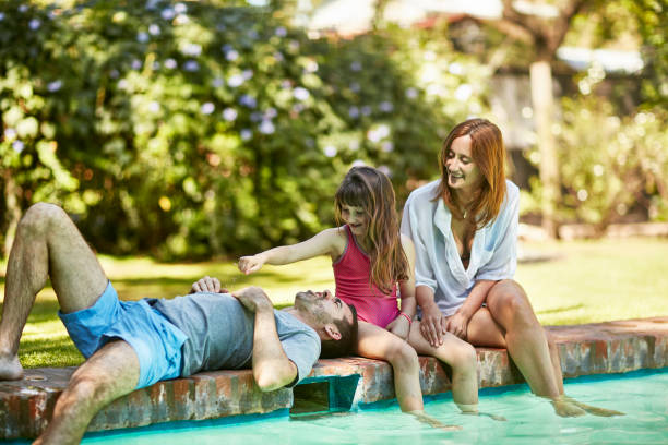 istock Young Family Relaxing Poolside in Sunny Backyard 1203903053