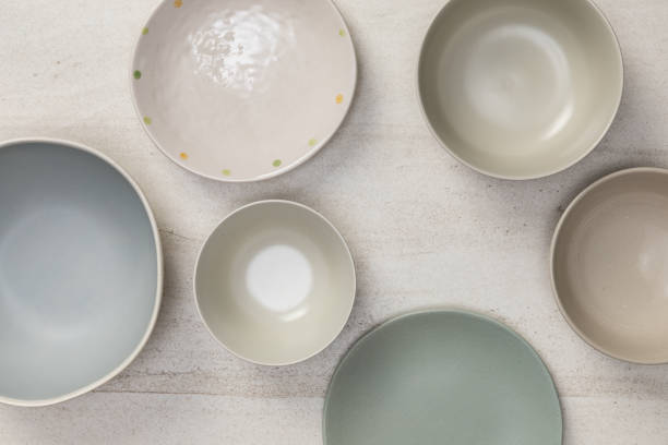 istock Group of empty blank ceramic round bowls and plates on white stone blackground, Top view of traditional handcrafted kitchenware concept 1203904371