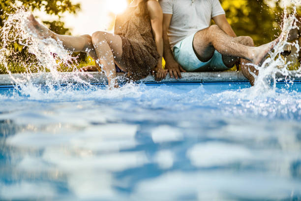 istock Unrecognizable couple having fun while splashing water in the pool. 1203904471