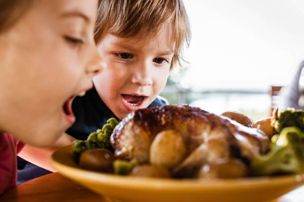 Cute kids about to eat roasted chicken meat and vegetables.
