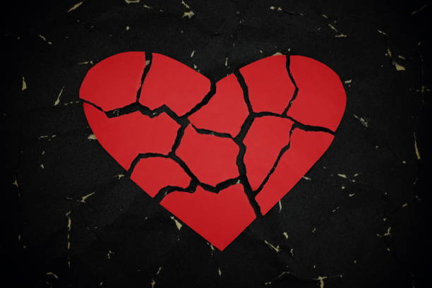 istock Broken red heart paper cutout on black background. 1203905776