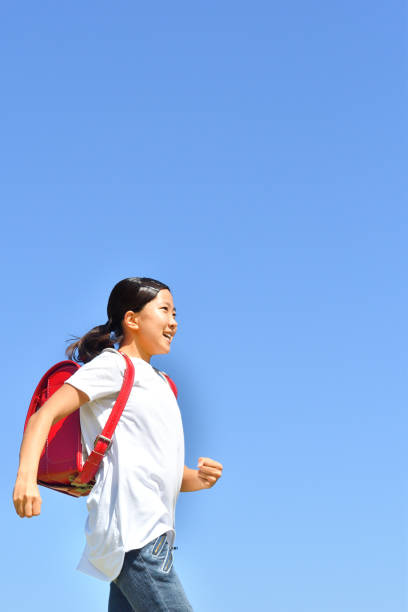 istock Japanese Elementary School Girl running in the Blue Sky 1203907054