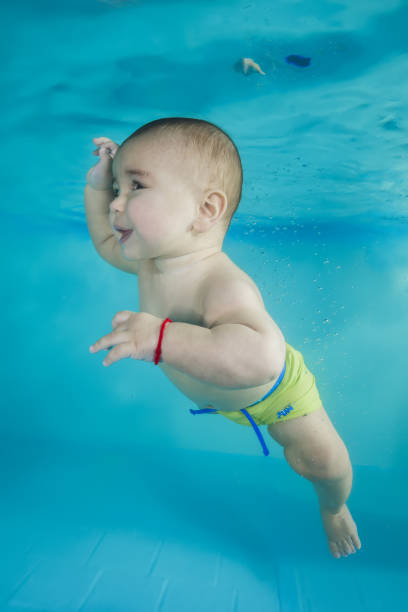 istock boy learns to dive underwater in a swimming pool 1203908747