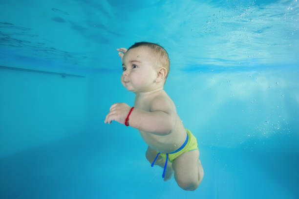 istock boy learns to dive underwater in a swimming pool 1203908756