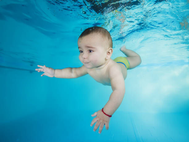 istock boy learns to dive underwater in a swimming pool 1203908795