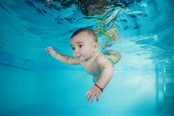 istock boy learns to dive underwater in a swimming pool 1203908799