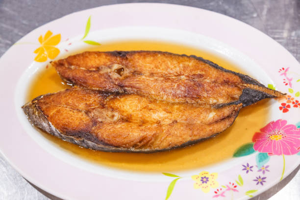 istock Delicious Natural Fresh Deep Fried King Mackerel Fish with Fish Sauce on white plate with table background. Thailand Food, Asian Cuisine, Thai Casual Food, Seafood and Street Food dish menu concept. 1203908922