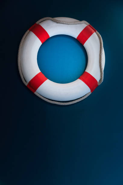 istock Bright Life Buoy in dark background. Personal life support flotation safety device for swimmers, passengers or marine personnel working in area exposed to water. Drowning Protection Equipment concept. 1203908984