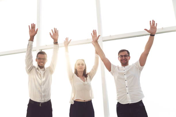 istock successful business team stands with hands up. 1203913915