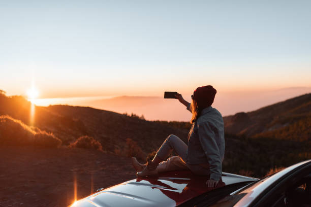 mujer disfrutando de la hermosa puesta de sol mientras viaja en las montañas en coche - paisaje no urbano fotos fotografías e imágenes de stock
