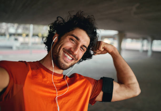 istock Confident smiling handsome sportsman taking a selfie and flexing muscles while looking into the camera 1203919803
